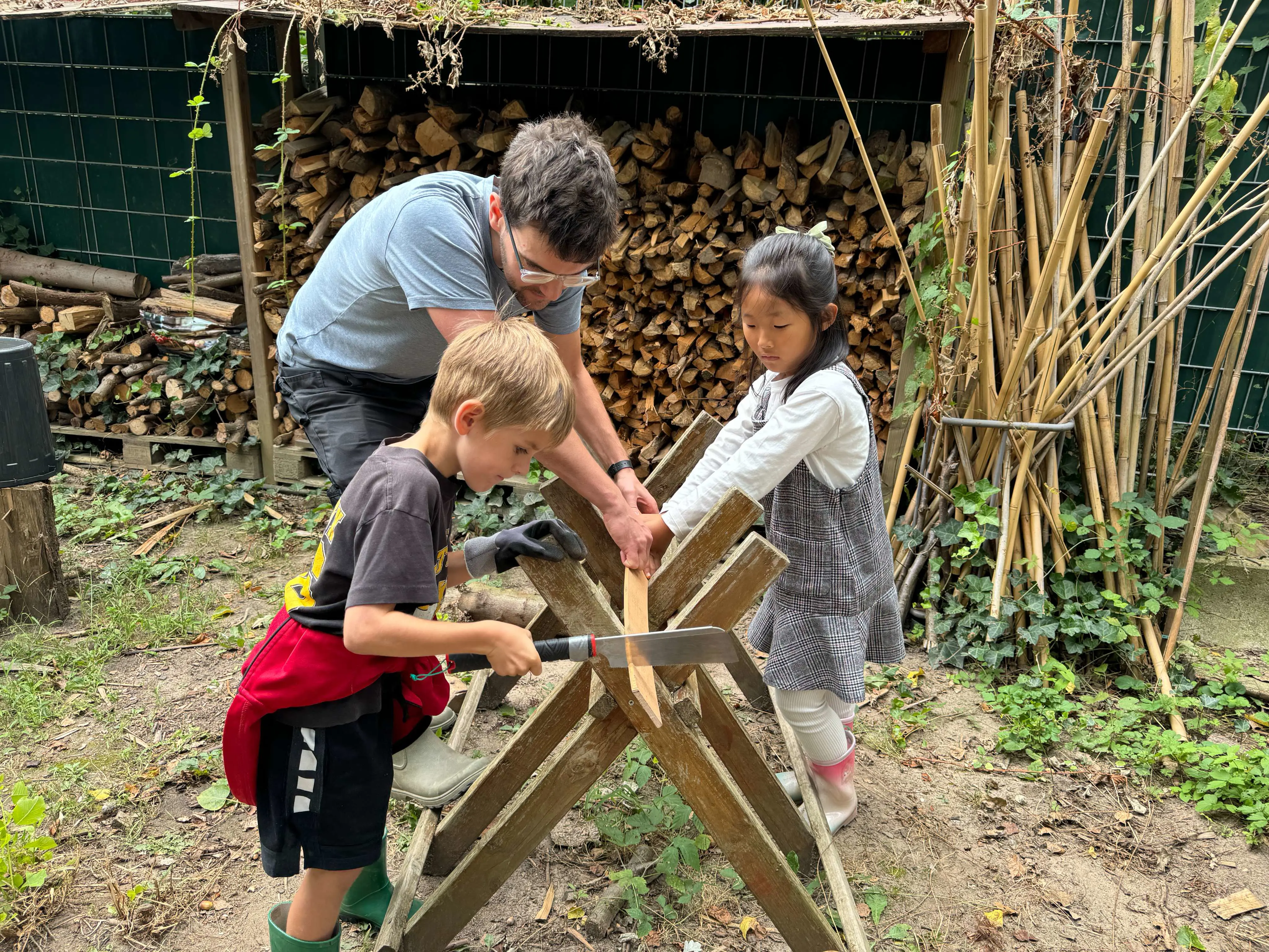 Young children using tools in an outdoor playground setting with teacher