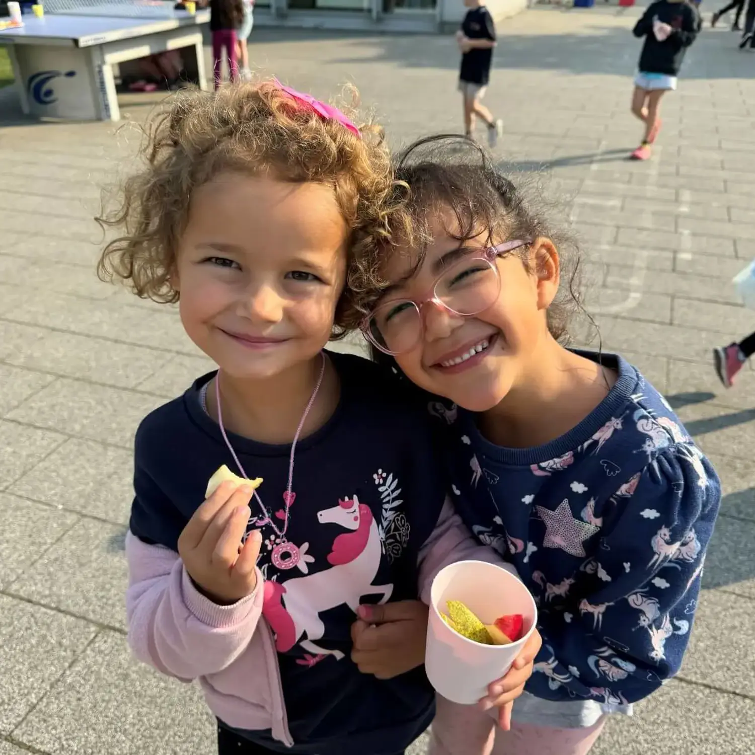 ISD pupils smiling and eating fruit together.
