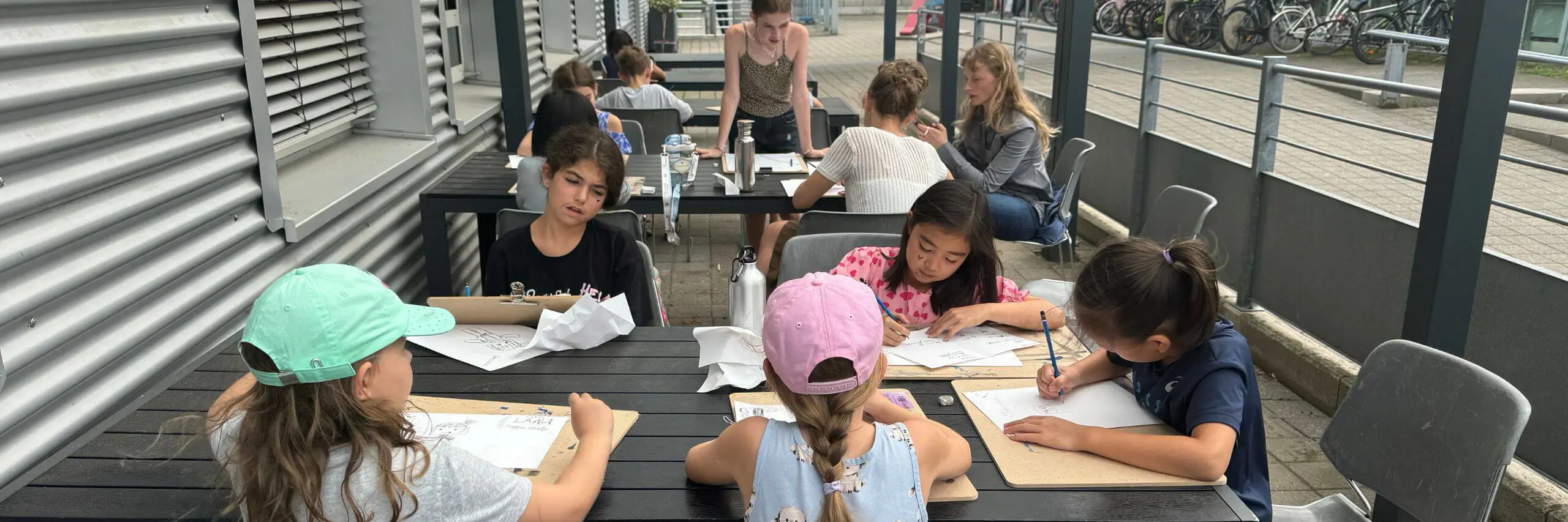 ISD Elementary pupils sitting outside and drawing.