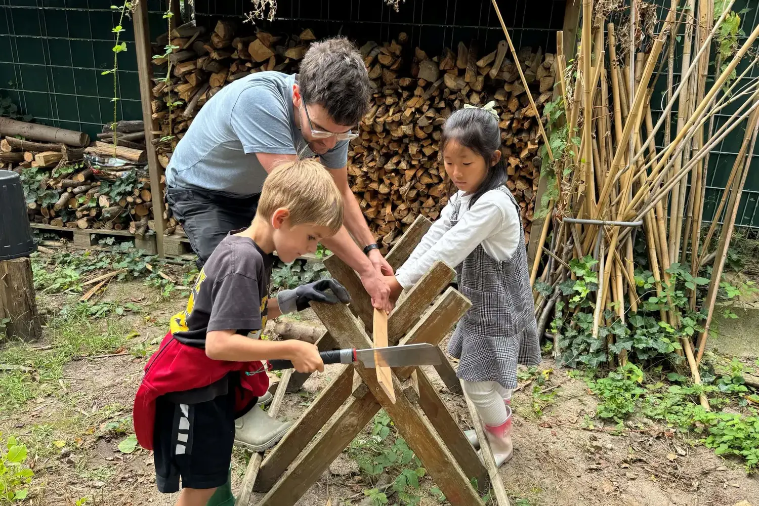Outdoor Learning Teacher helping students to saw through a branch.