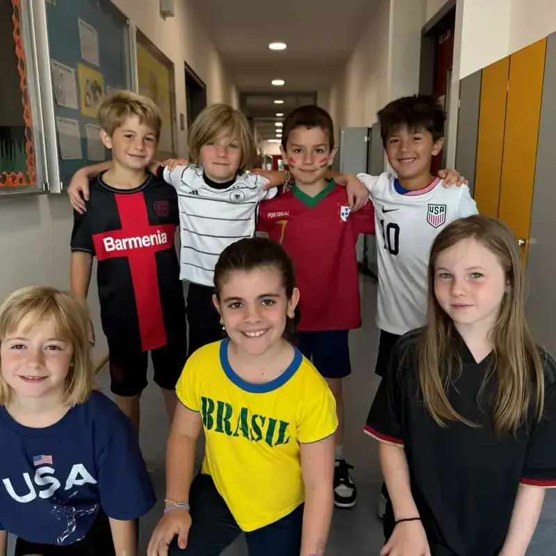 Young elementary students posing for a group photo inside the campus hallway.